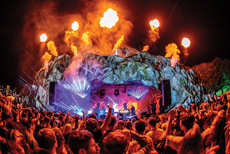 music festival stage with lights and fireballs above it